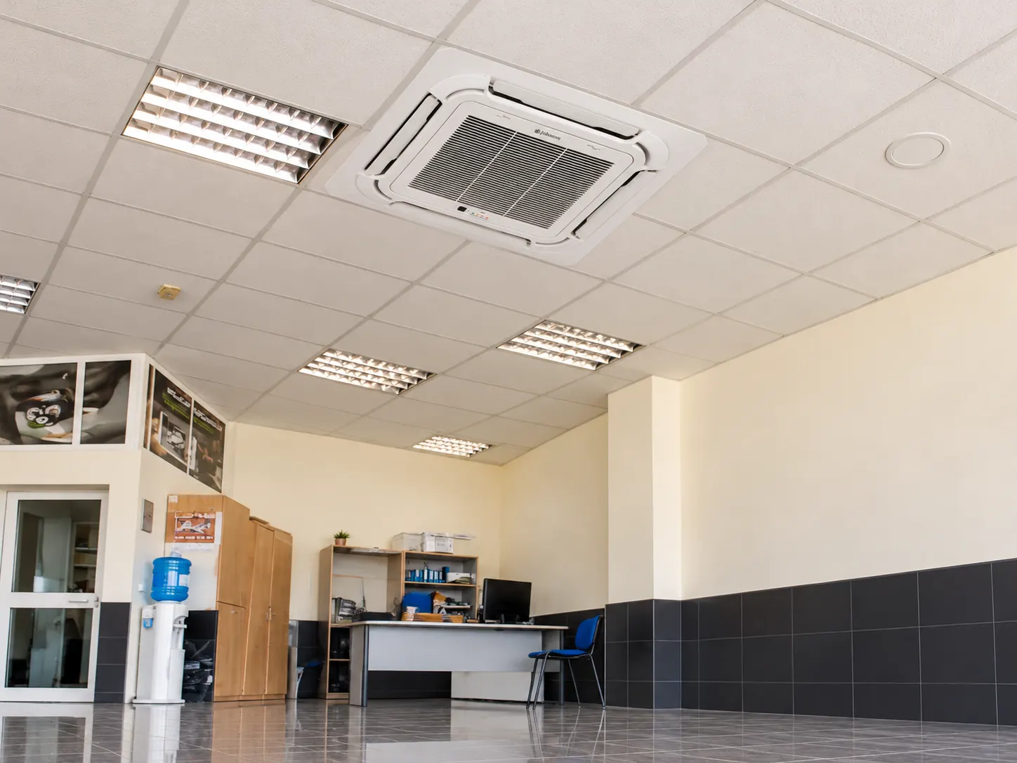 White four-way ceiling cassette air conditioning unit fitted into a suspended tiled ceiling